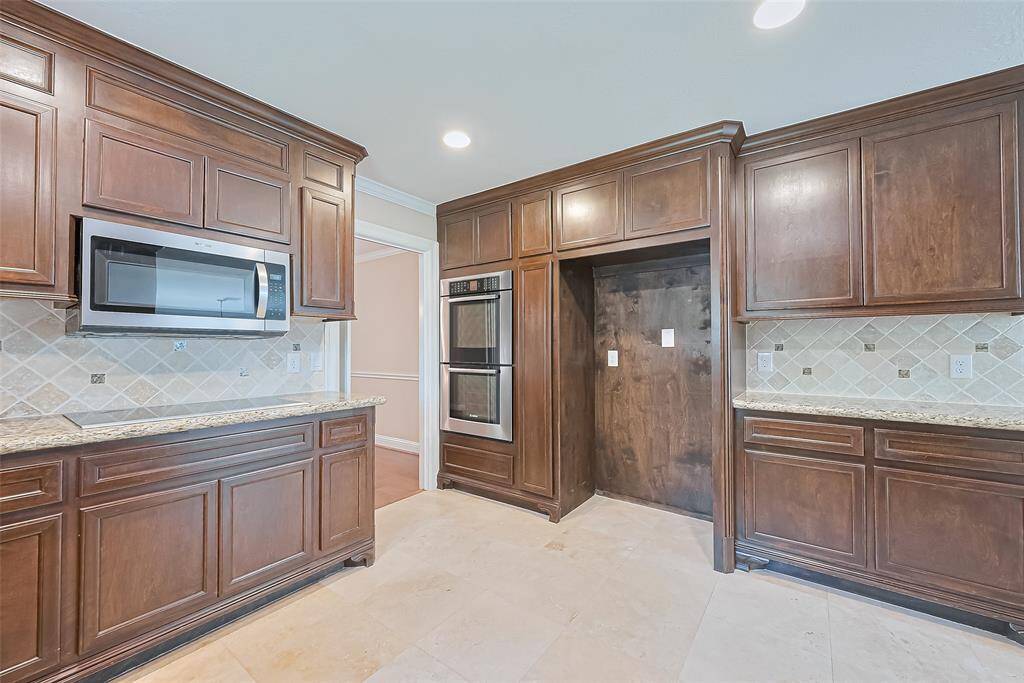 Modern kitchen featuring stainless double ovens, a built-in microwave, and ample space for a full-size refrigerator.