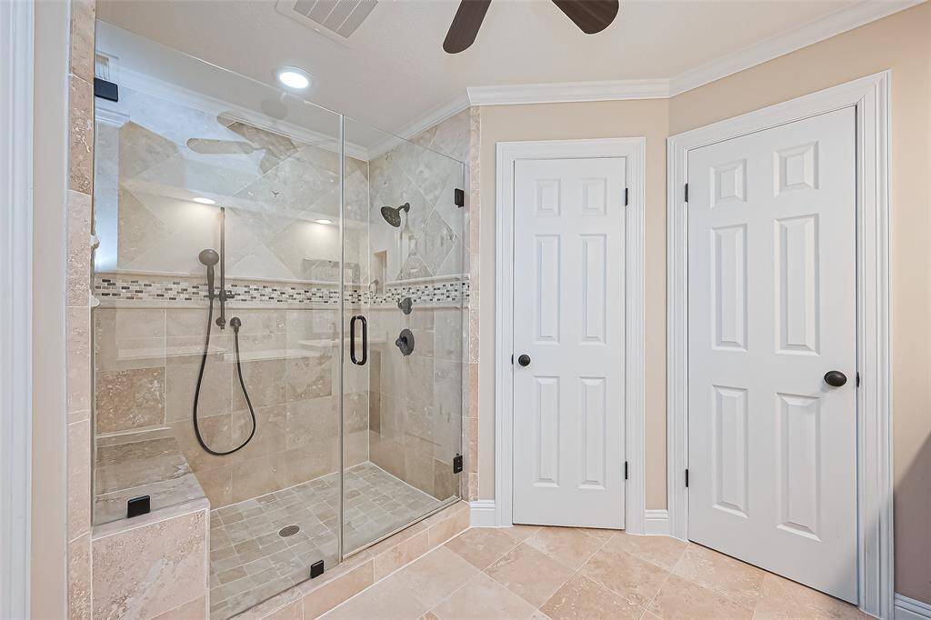 Luxurious primary ensuite bath featuring a spacious, glass-enclosed shower and elegant tilework for a spa-like retreat. There are also two walk-in closets.