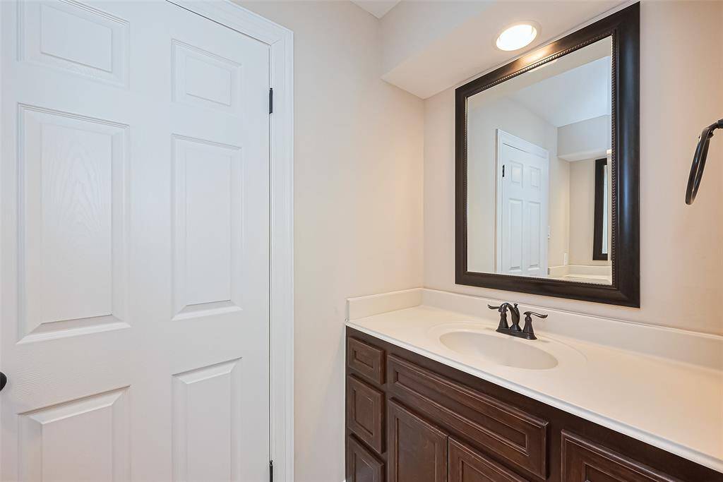 This secondary bathroom features two separate modern vanities with a dark wood finish, a sleek countertop, and a stylish black-framed mirror. It has a clean, neutral color palette and recessed lighting for a bright, inviting atmosphere.