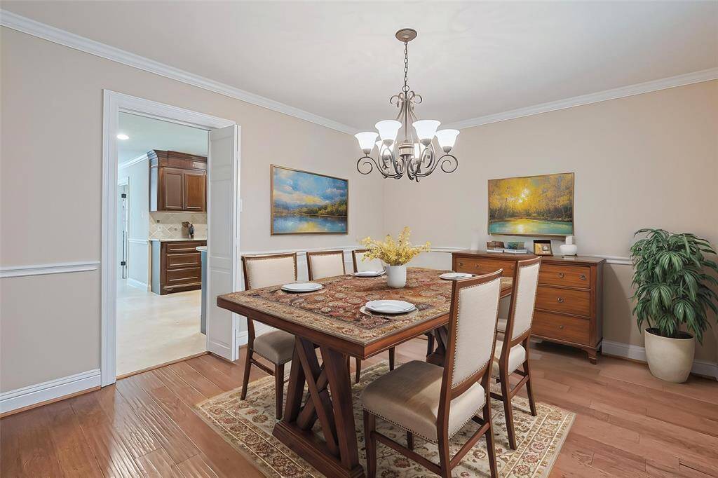 Virtually staged. Elegant dining room designed for memorable gatherings, with access to the kitchen. It features a stylish chandelier and engineered wood floors.