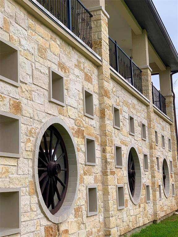 Impressive wagon wheel details line the porte chocere. Also, notice the second story outdoor balcony that extends the length of the left side of the home.