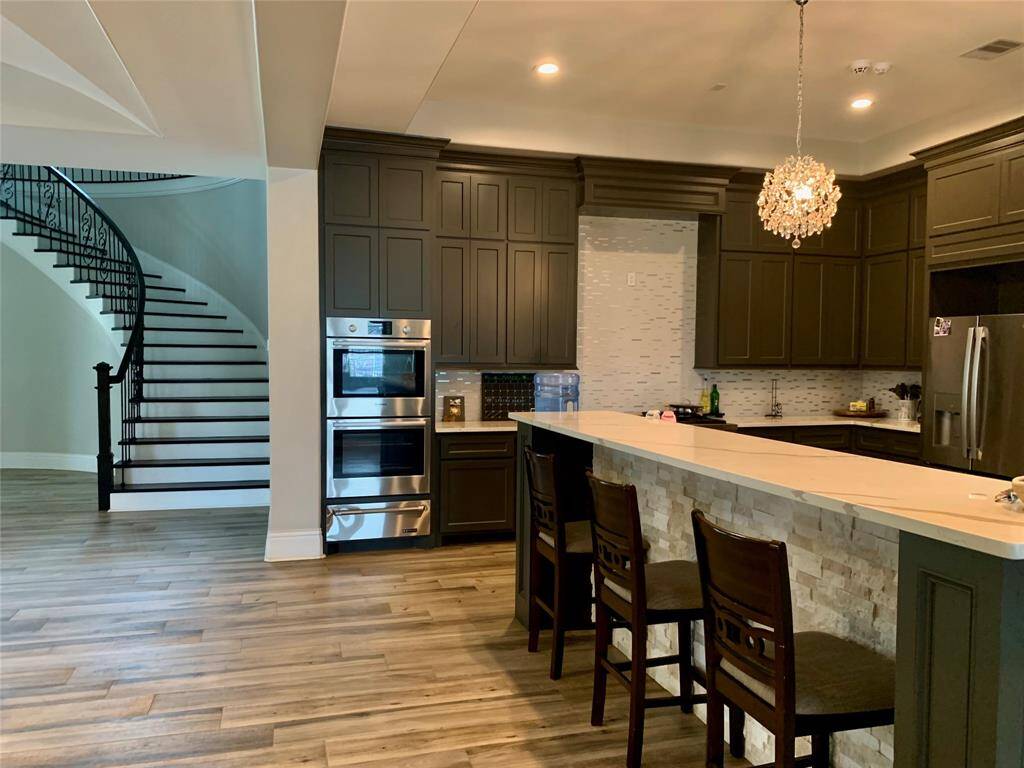 Open concept kitchen has a view of dining room, living room, den and beautiful stairway.