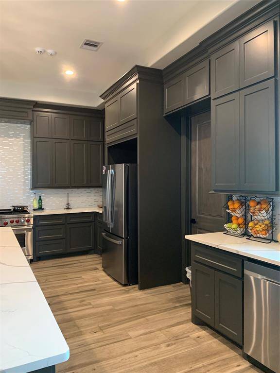 View of door leading to the walk-in pantry and dishwaher, fridge and stove.