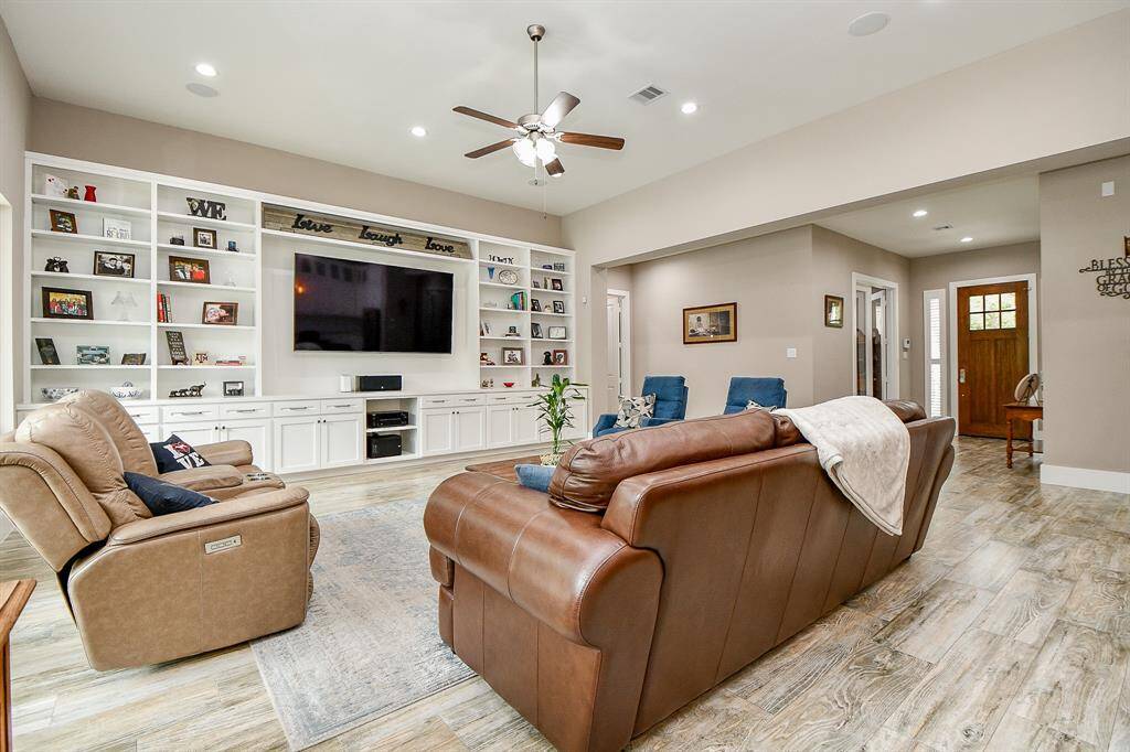 The wonderful stylish full wall of built-in shelves with ample storage surrounding a large 82 inch TV are which will stay with the home. High ceilings and recessed LED lighting.