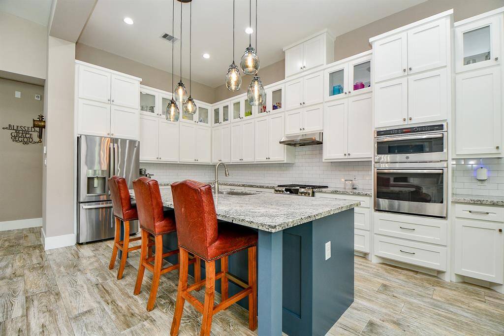 This modern kitchen features a huge walk-in pantry with a built-in wine rack. Stainless steel appliances, 5-burner gas stove top, double ovens, microwave/convection. The French door refrigerator will stay with the home.