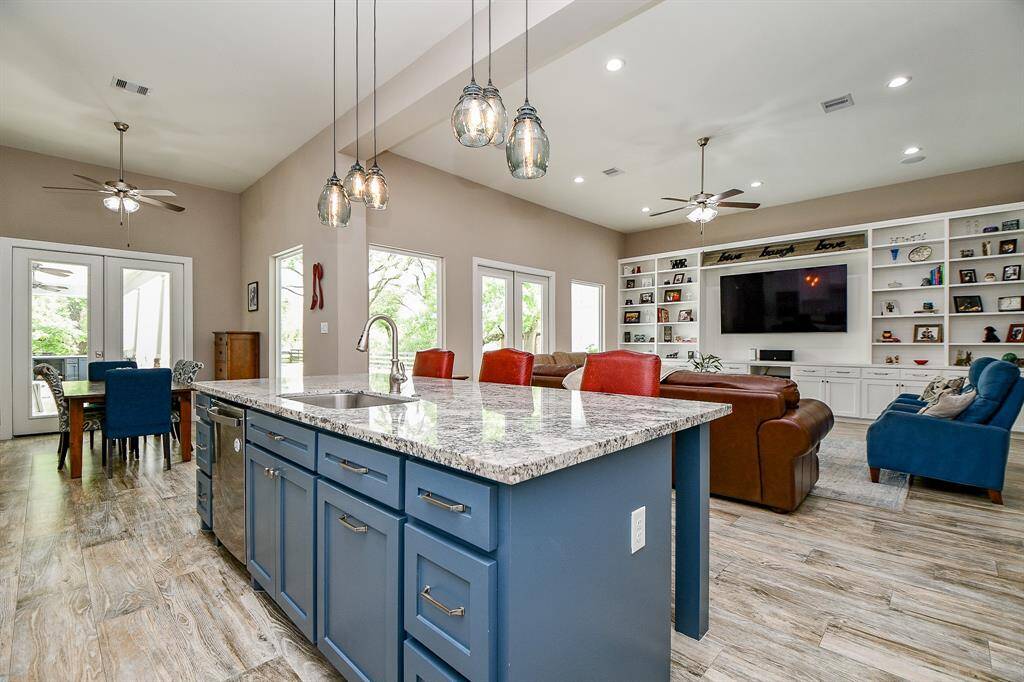 This modern kitchen features a bold blue island and flows effortlessly into the open-concept living area. Glass doors lead to the dining space and beyond, creating a seamless connection to the outdoors.