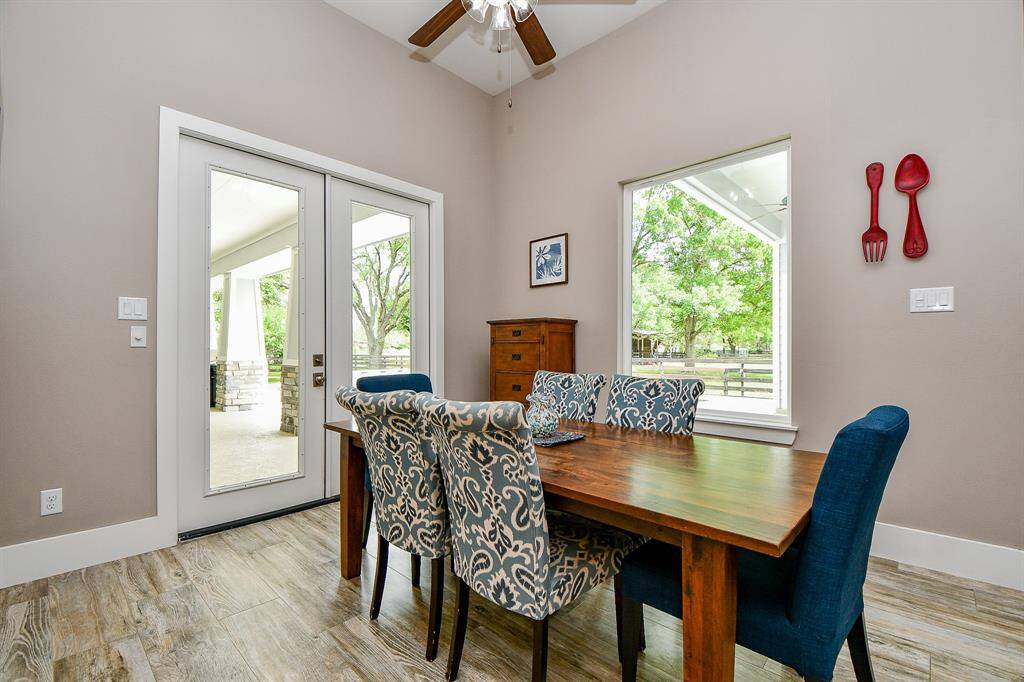 The dining area offers ample space for gatherings and everyday meals. French doors open to the covered patio and outdoor kitchen, while large windows fill the room with natural light and views of the backyard.