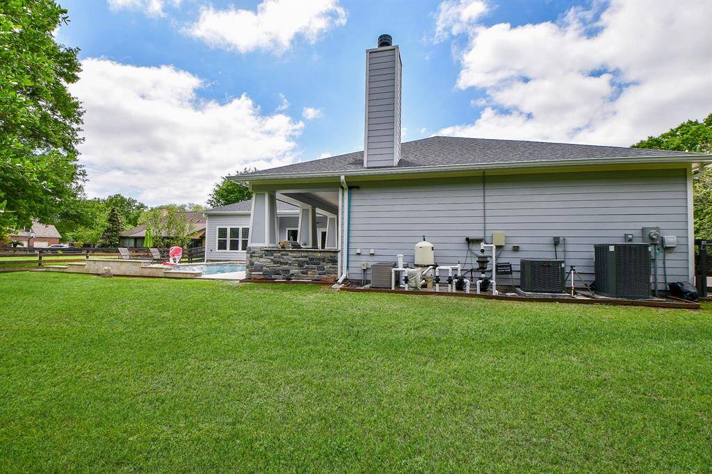 A partial view of the large backyard, pool area and the pool equipment outside the garage. The setting is bright and open, ideal for outdoor activities and relaxation.