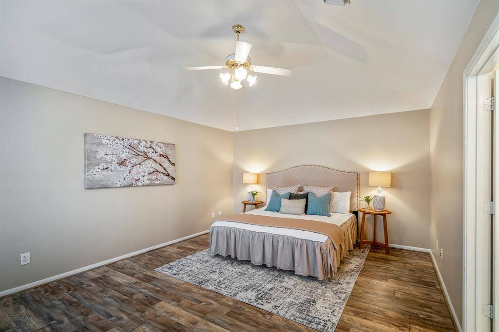The spacious primary bedroom features laminate flooring and a vaulted ceiling, creating a bright and airy retreat with plenty of room to unwind.