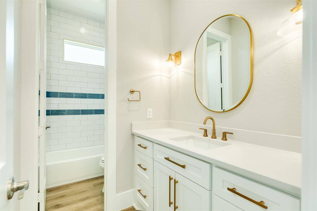 Elegant guest bath featuring gold/brass fixtures and a stylish tiled bath/shower.