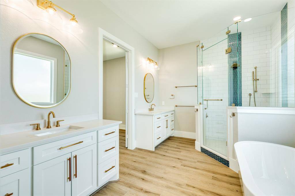 Elegant white ensuite bathroom featuring luxurious brass fixtures, dual vanities, and water closet.