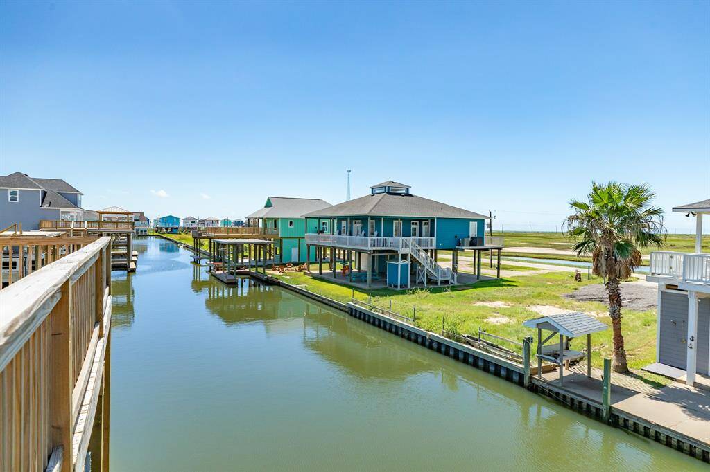 This photo showcases a waterfront property with a canal view. The house features elevated construction, a spacious deck, and a serene setting ideal for enjoying water activities and coastal living.