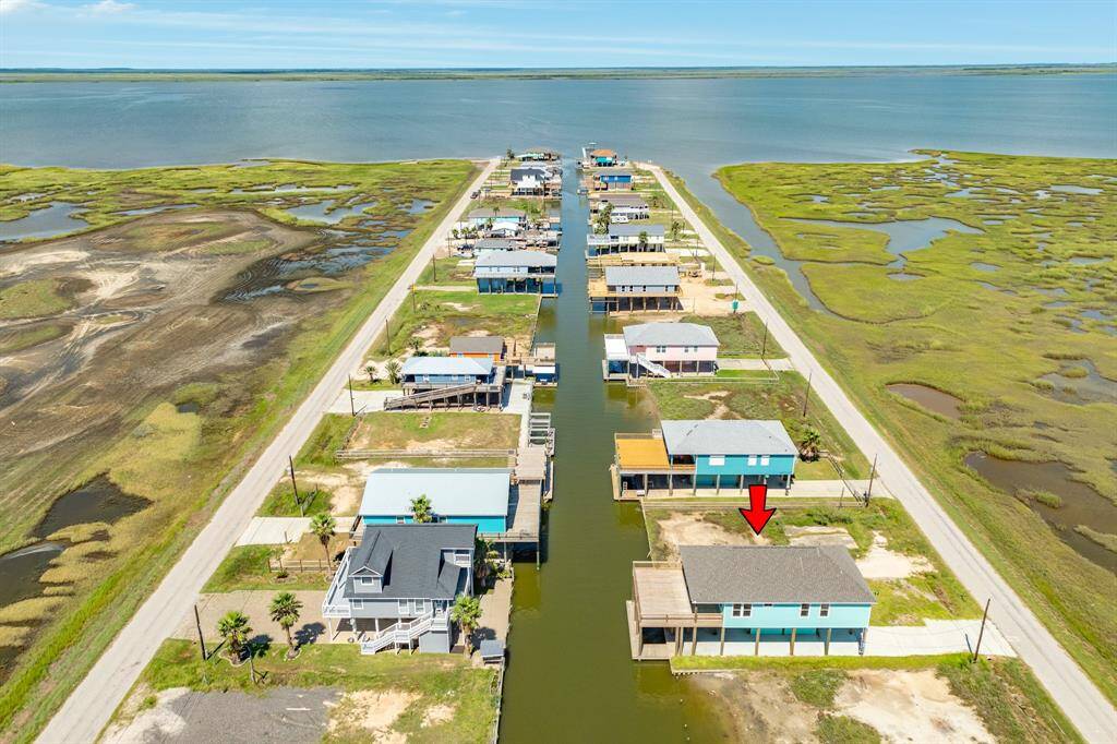 This aerial photo showcases the Key Largo waterfront community with homes lining a canal, offering direct water access. The area is surrounded by lush marshlands and open water views, providing a serene and picturesque setting ideal for boating and nature enthusiasts.