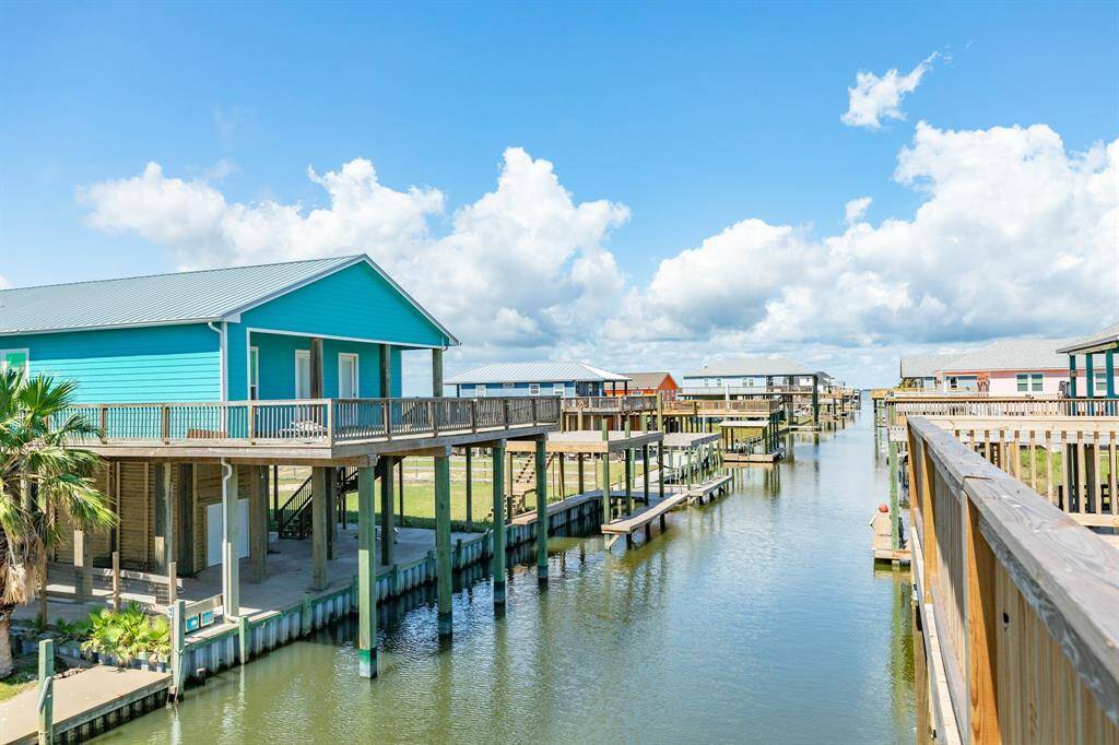 This waterfront property features a vibrant home with a spacious deck overlooking a serene canal, perfect for boating enthusiasts. The setting offers a picturesque view with ample outdoor space and dock access.