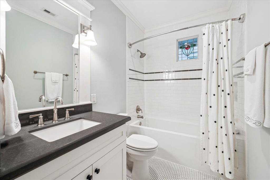This guest bathroom sits between the two secondary bedrooms and features beautiful subway tile, a deep soaking tub, a caesar stone countertop, and ample storage.  Notice the stained glass window that was saved from the original bungalow.