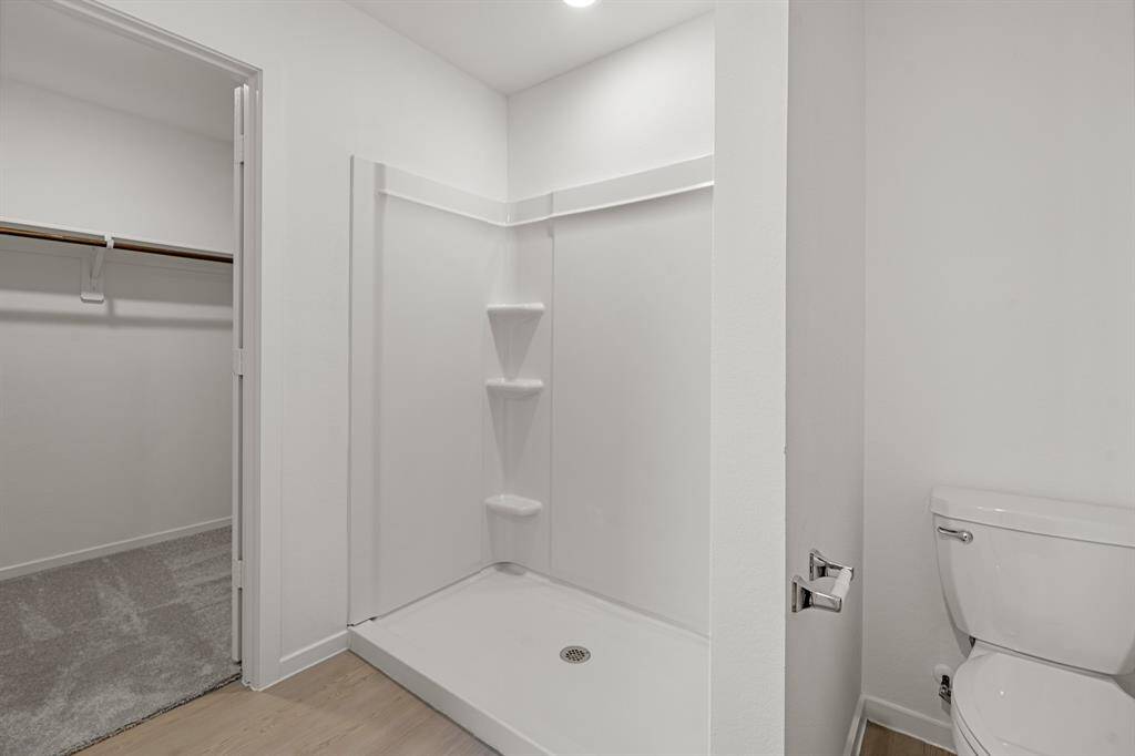 This incredible primary bathroom features vinyl plank floors, and a gorgeous walk-in shower.
