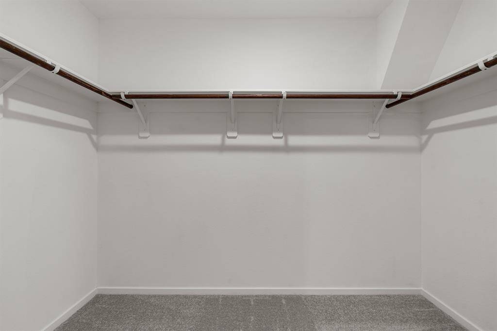 The walk-in closet in this primary bedroom is very spacious, and has carpet floors.