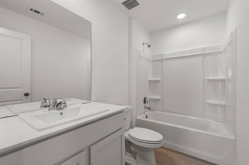 Secondary bathroom featuring vinyl plank floors, recessed lighting, quartz countertops, and a shower/tub combo.