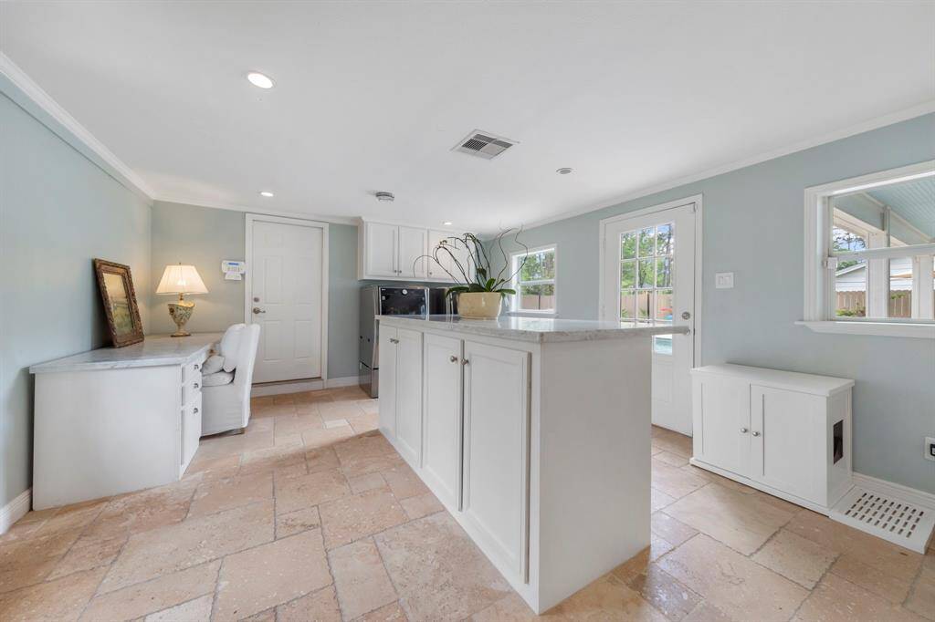 Beyond the kitchen is an expansive mudroom offering convenient access to the backyard, 3-car garage, and side entrance. This functional space includes a large island with storage, a built-in desk, dedicated washer and dryer area, and plenty of additional storage to keep everything organized.