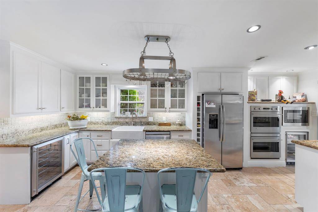 Equipped with dual beverage refrigerators, a dishwasher, full-sized refrigerator, double ovens, a farmhouse sink, and a microwave for ultimate convenience.