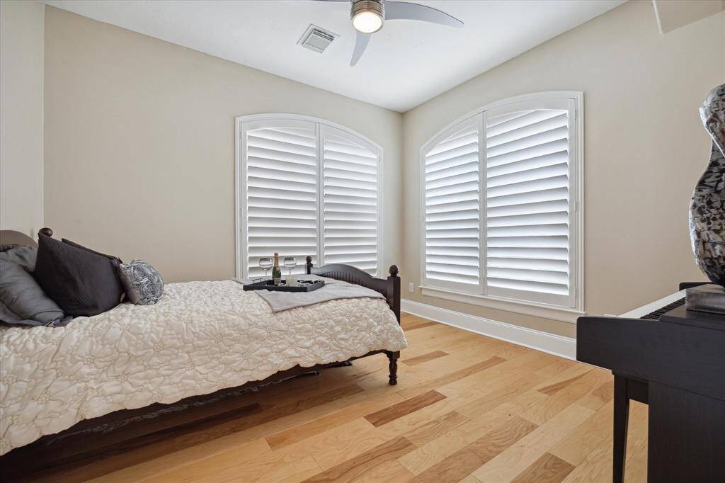Secondary Bedroom complete with wood floors, plantation shutters and a ceiling fan