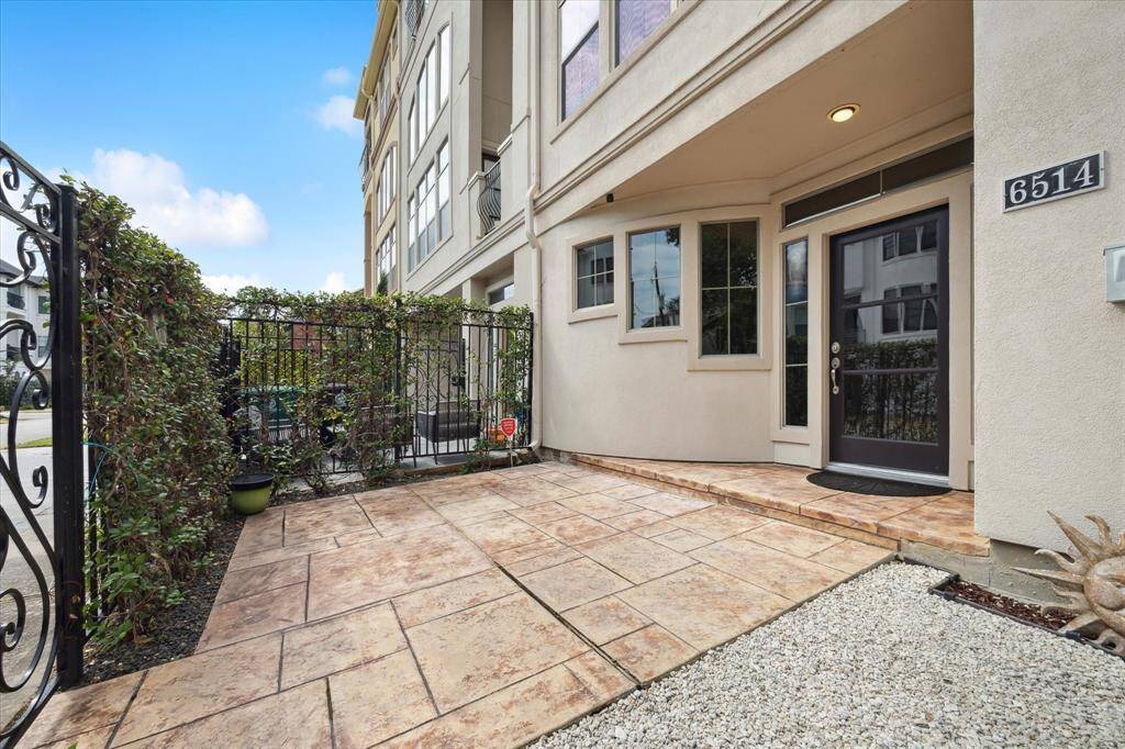 The front patio sits behind a private wrought-iron fence and gate