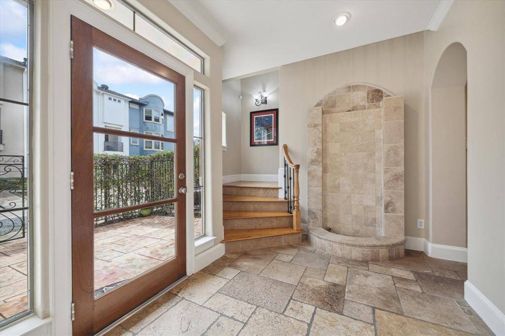 Beautiful travertine floors in this entry behind a wood and glass front door