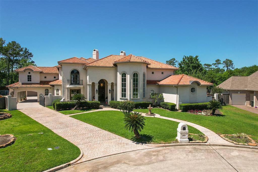 This elegant home features a grand exterior with a Mediterranean-style design, complete with a red-tiled roof and large arched windows. The manicured front lawn and spacious driveway enhance its curb appeal, offering a luxurious and inviting atmosphere.