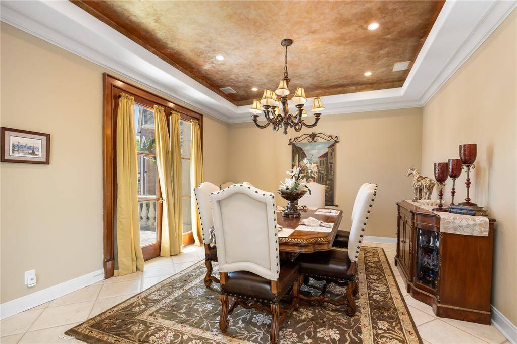 The dining room provides a warm and inviting atmosphere featuring a sophisticated chandelier, ornate ceiling, and large windows, providing an abundance of natural light for the beautiful space.