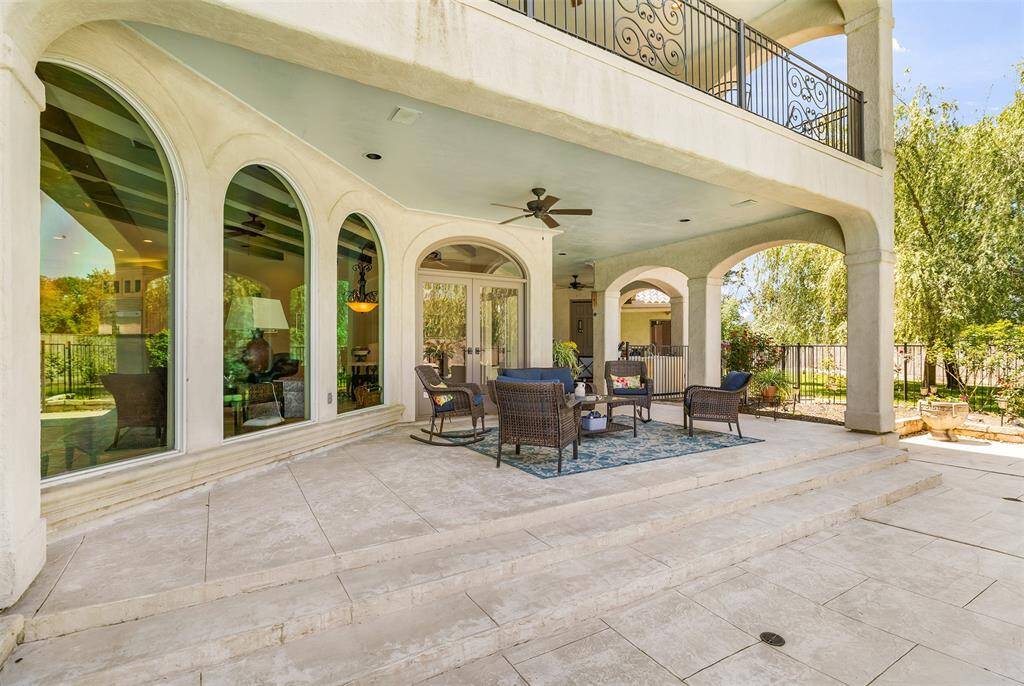 This elegant patio offers a seamless indoor-outdoor living experience, featuring arched openings and large windows that invite natural light. Cozy seating and ceiling fans create a comfortable ambiance, while the space overlooks a beautifully maintained garden—perfect for both relaxation and entertaining.