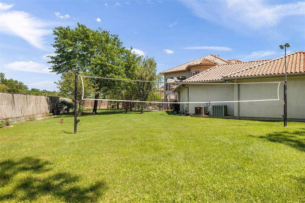 Spacious backyard features a well-maintained lawn and volleyball space. The area is fenced for privacy, creating a fun and inviting space for outdoor recreations.