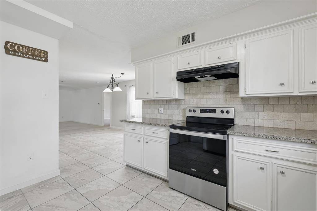 The kitchen is equipped with a sleek electric range oven and features stunning granite countertops that add both style and durability.Perfect for everyday cooking or entertaining, this space blends function with timeless design.
