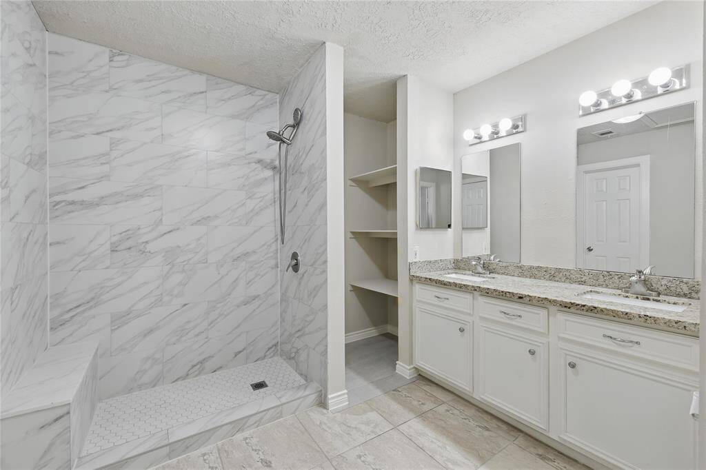 The bathroom features a walk-in shower with a built-in bench, offering both comfort and convenience.You'll also enjoy dual sinks with elegant granite countertops, combining style and functionality for a luxurious experience.
