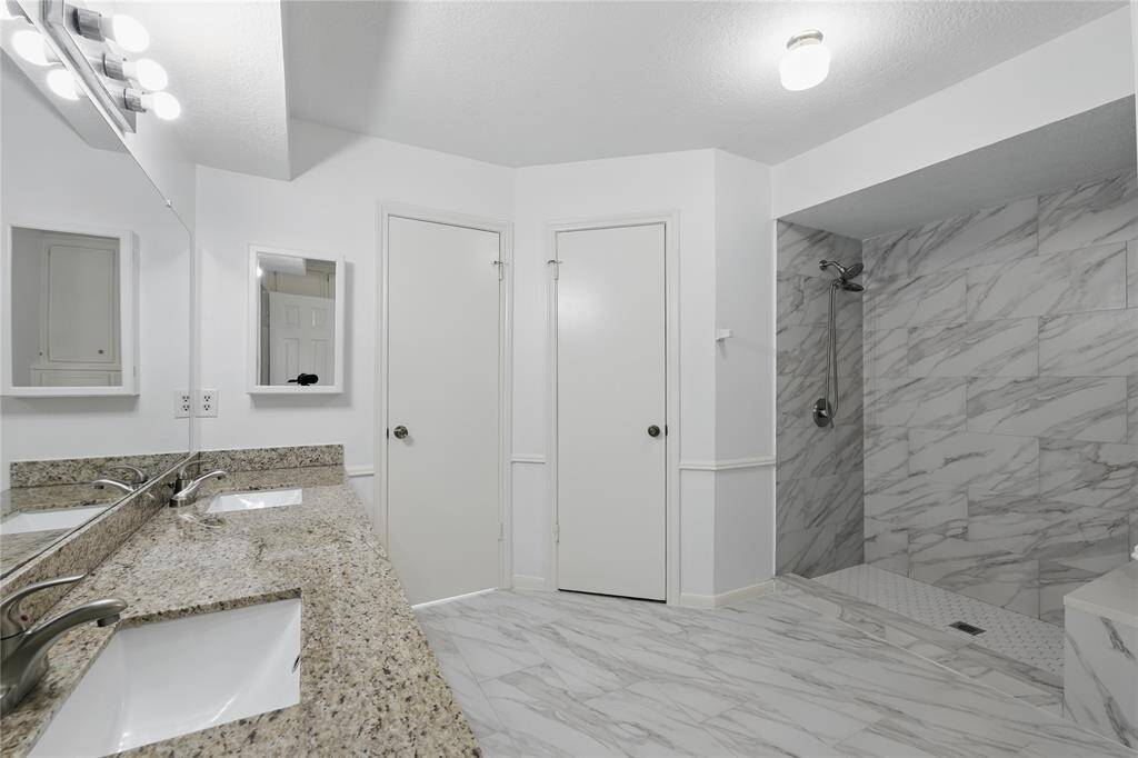 The primary bathroom features dual sinks, a sleek modern walk-in shower with a built-in bench, and a separate toilet room for added privacy.With both his and hers closets, this space offers convenience and plenty of storage, combining luxury and practicality for your daily routine.
