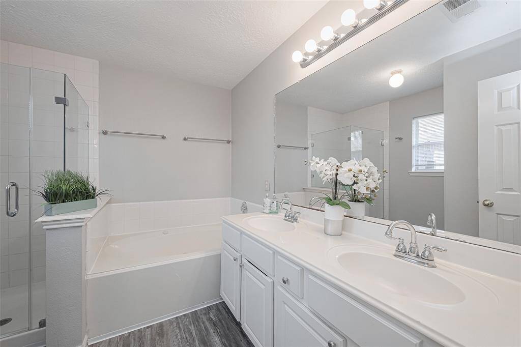This bathroom boasts a double sink vanity, offering ample space for your morning routine. Pamper yourself in the luxurious jetted tub, perfect for unwinding after a long day. For those who prefer a quick refresh, there's also a separate stand-in shower. This bathroom combines functionality with indulgence, creating a tranquil retreat within your home.