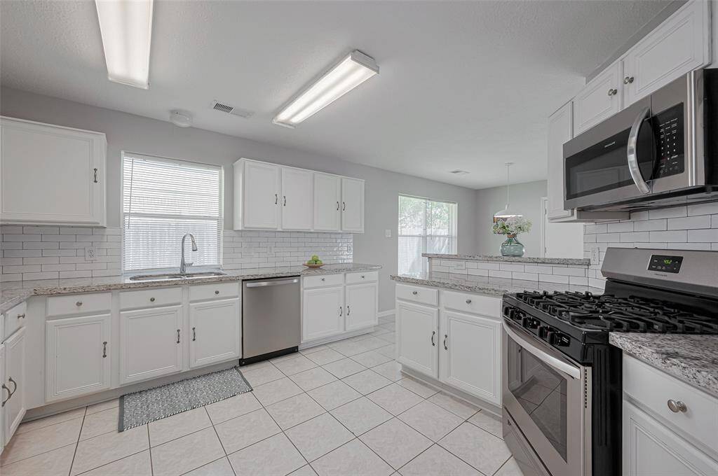 The bright and functional kitchen is ready for your culinary adventures. Featuring white cabinetry, stainless steel appliances, and ample countertop space, it's a chef's delight.