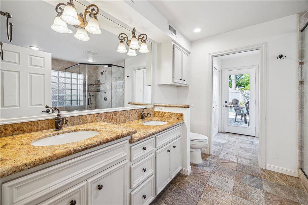 Primary bathroom includes double sinks, jetted tub, stand along shower, granit countertops, two closets and connects easily to outdoor patio perfect for midnight swims!