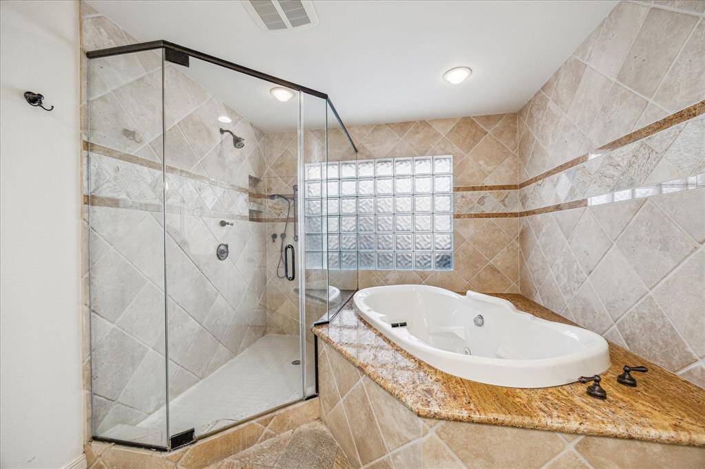 The primary bathroom features a spacious standalone shower and a luxurious jetted tub.