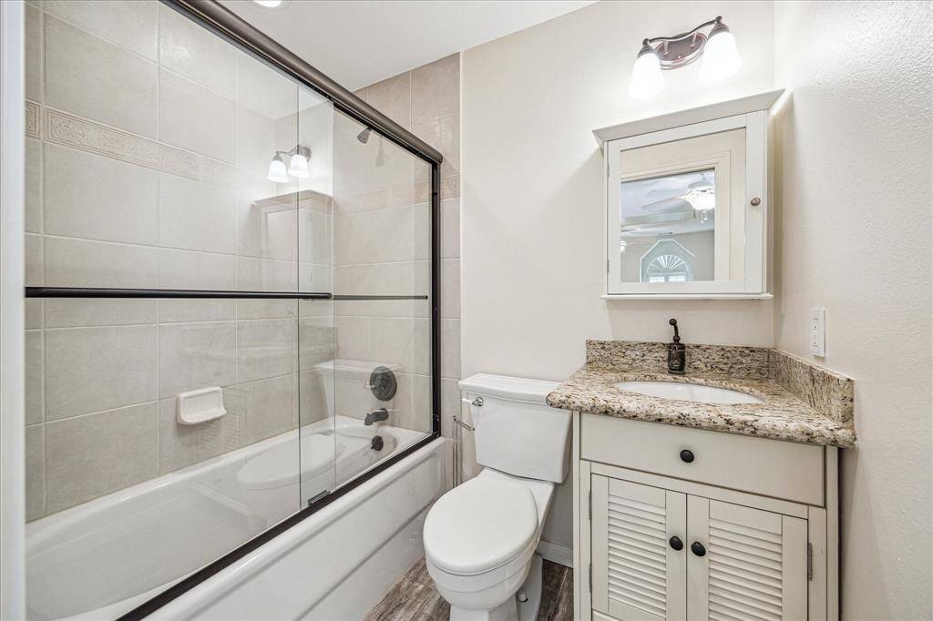 Secondary en-suite full bath with shower/tub combo and granite countertops connects to large bedroom.
