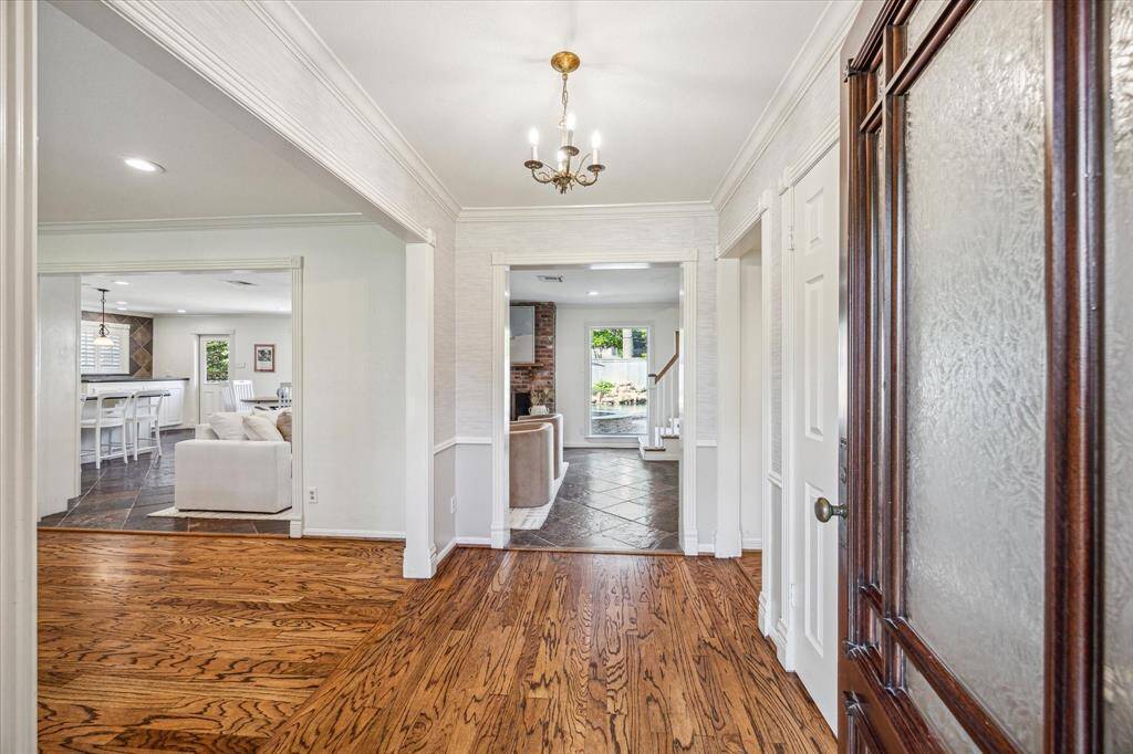 Polished hardwood floors welcome guests, creating a striking first impression with views of the expansive open-concept living area and the glistening pool outside.