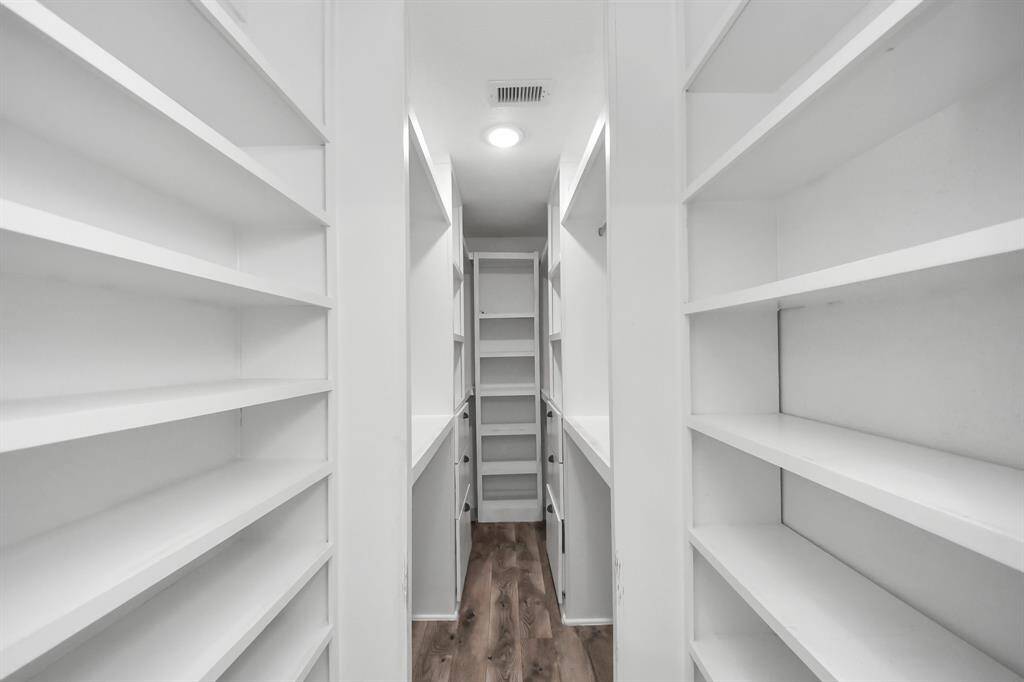 Primary bedroom closet with built-in cabinetry.