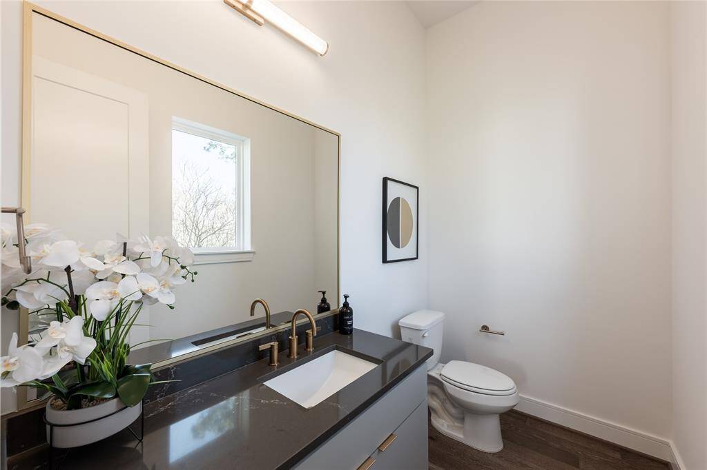 A bold contrast of sleek black counters and light walls creates a striking, modern powder bath.