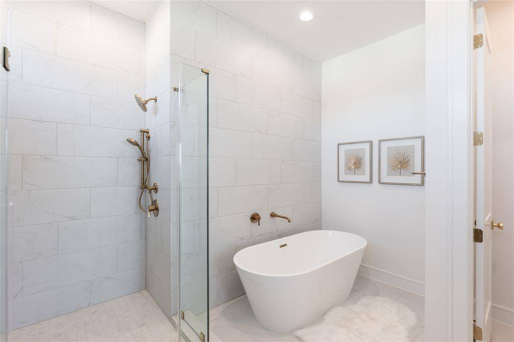 The seamless integration of form and function defines this tranquil bathroom retreat with a frameless glass walk-in shower and separate bathtub.