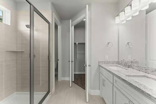 Primary bathroom features a double vanity, expansive mirror, and a sleek glass-enclosed shower.