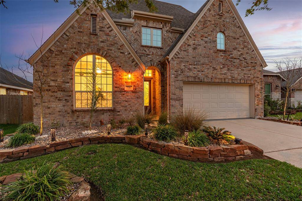 Charming Highland Home Ashwood with well-maintained front yard, featuring an arched entrance and covered front porch. The property includes a double driveway leading to a 3-car garage and Radiant Barrier in the attic for energy efficiency.