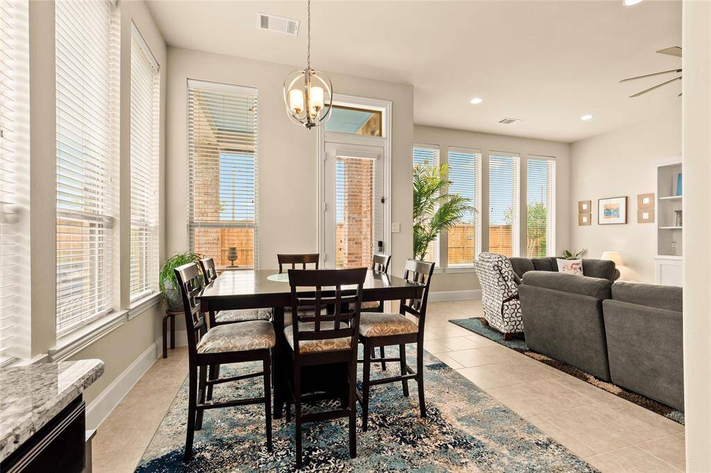 Updated interior lighting & fixtures with dimmable features. Large windows surrounding the breakfast area fill the space with natural light, highlighting a cozy breakfast area. The neutral color palette and modern light fixture add a touch of elegance, while a view of the outdoor area enhances the inviting atmosphere.