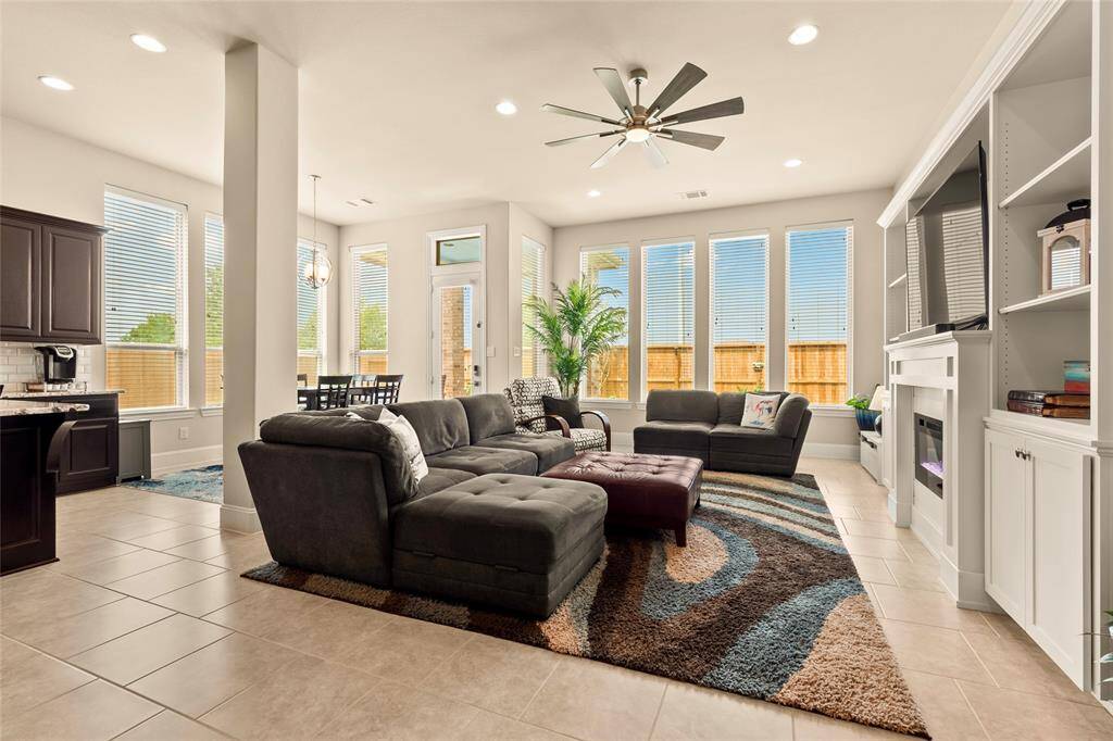 Spacious family room features 11-foot ceiling, a built-in entertainment center and a wall-of-windows for ample natural light, while the adjacent dining area and kitchen offer seamless flow for entertaining.