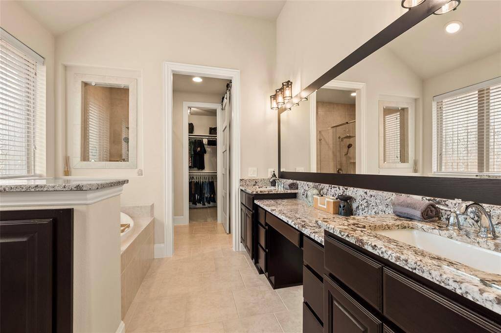This spacious Primary bathroom features a double sink with granite countertops, ample storage, and a framed mirror.The walk-in closet is easily accessible, enhancing convenience.