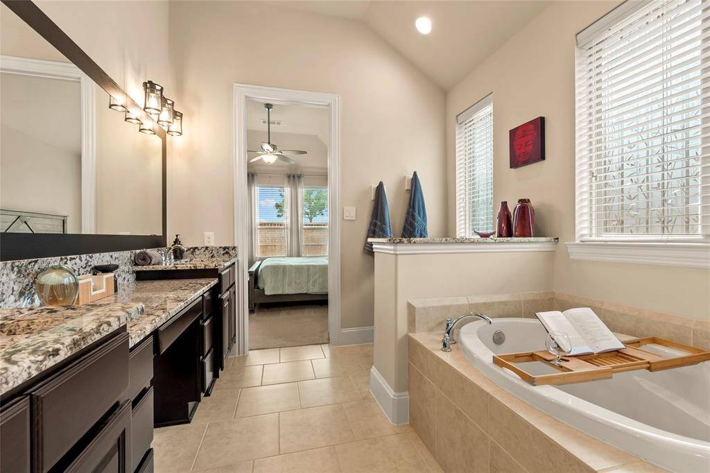 Modern bathroom with luxurious soaking tub, a separate shower, and vanity area. Natural light streams in through twowindows, enhancing the neutral color palette.