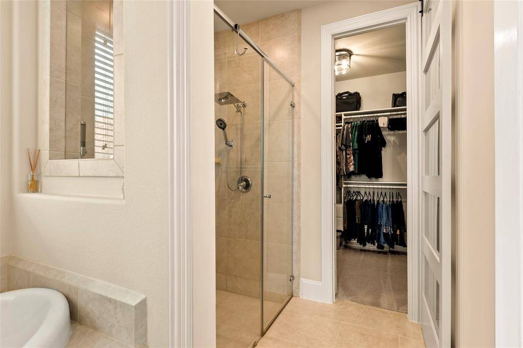 8-foot high interior doors throughout. Glass-enclosed shower and a walk-in closet. The space is well-lit, featuring neutral tones and a clean, organized appearance.